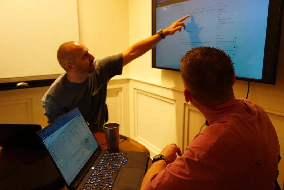 Sammy pointing at a discount setup on the big screen while Dave looks on